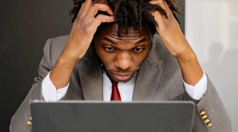 an exhausted man working in front of his laptop